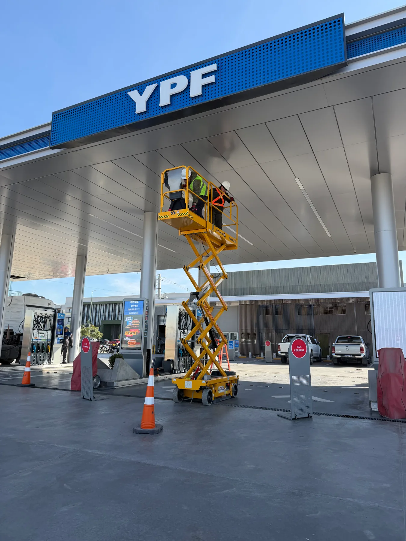 Técnicos de DOMATIC trabajando sobre plataforma elevadora en la marquesina de una estación de servicio YPF