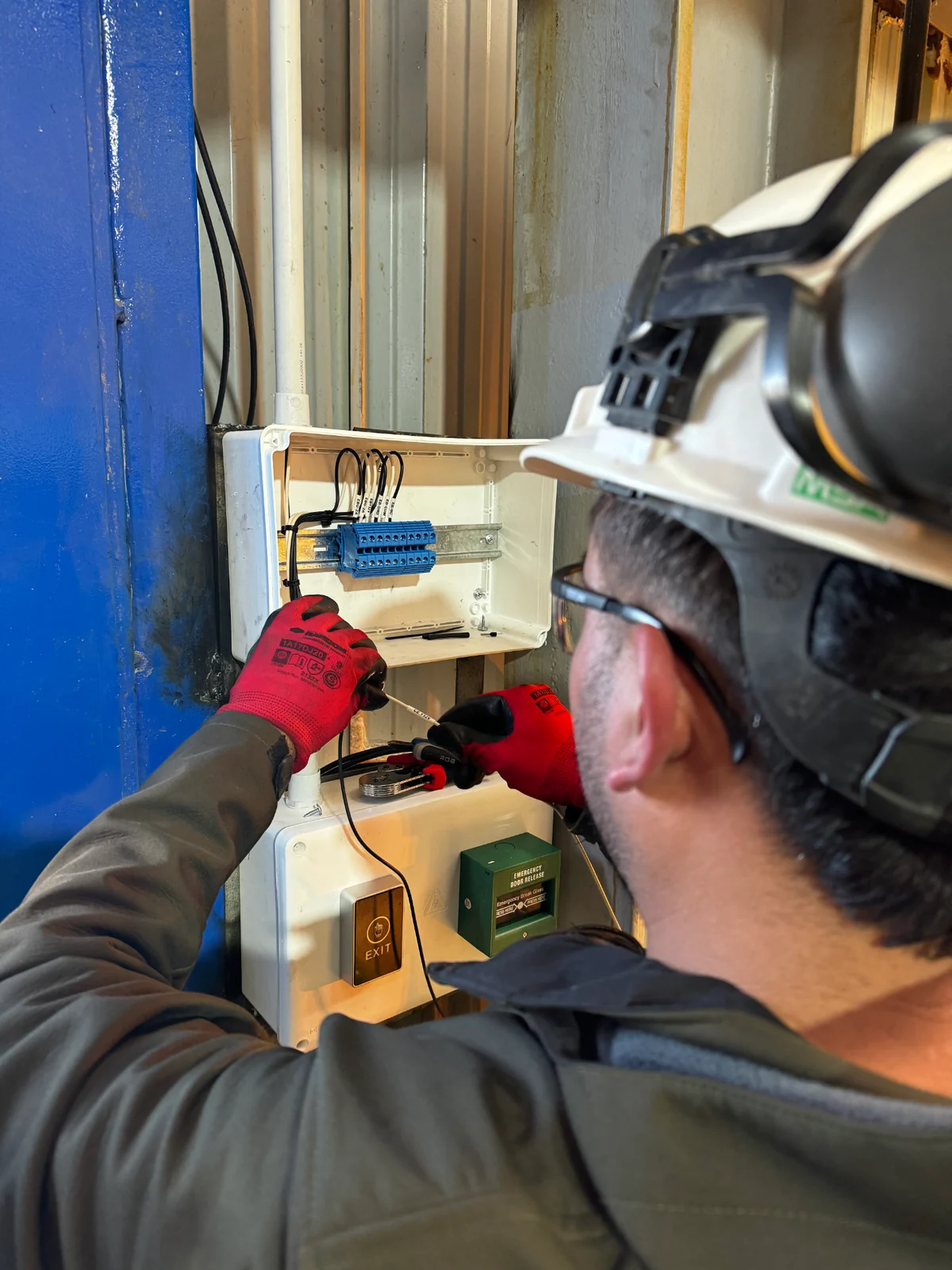 Técnico de DOMATIC trabajando sobre el tablero del sistema de control de acceso en planta industrial